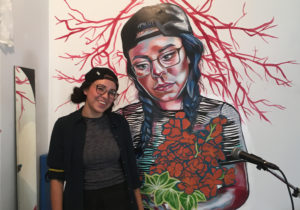 Lauren Crazybull standing with her mural